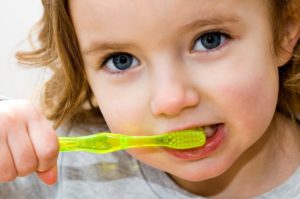 Young girl at pediatric dentist in Northampton brushing her teeth.