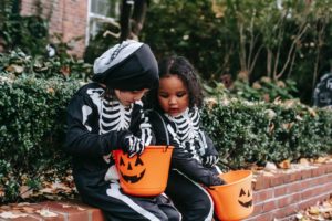  Two children looking in Halloween candy buckets