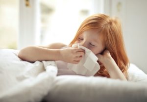 Young girl blowing her nose